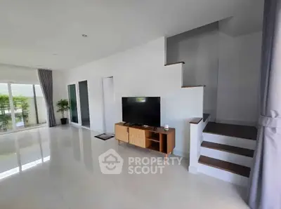 Spacious modern living room with sleek staircase and large windows for natural light.