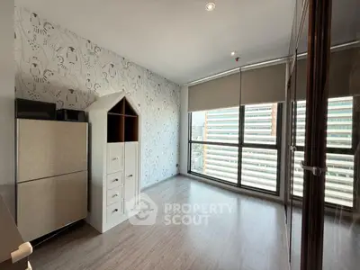 Spacious room with modern decor and large windows offering city views.