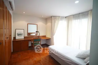 Spacious bedroom with wooden floors and large windows for natural light.
