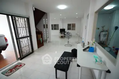 Spacious open-plan living area with modern decor and natural light, featuring a sleek black bench and a stylish fan.