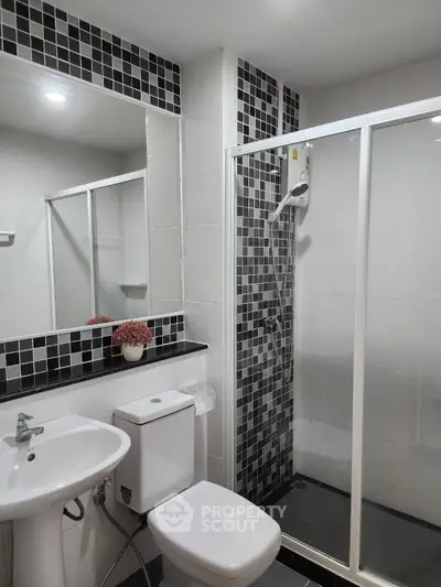Modern bathroom with sleek shower and stylish black-and-white tile design.