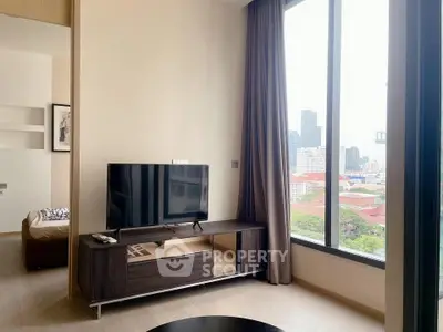 Modern living room with city view, featuring sleek TV stand and large window for natural light.