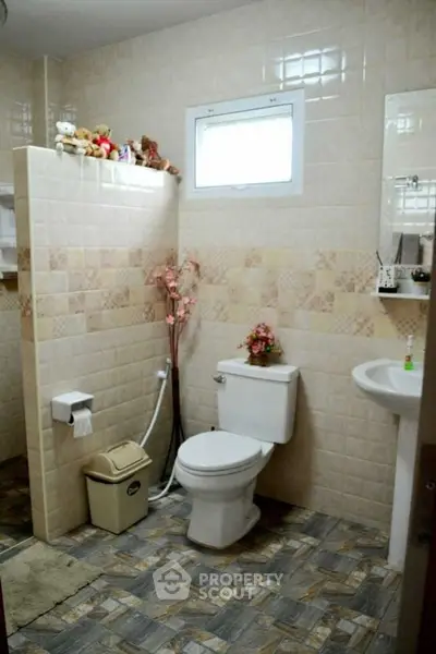 Charming bathroom with tiled walls and floor, featuring a toilet and sink, perfect for cozy home living.