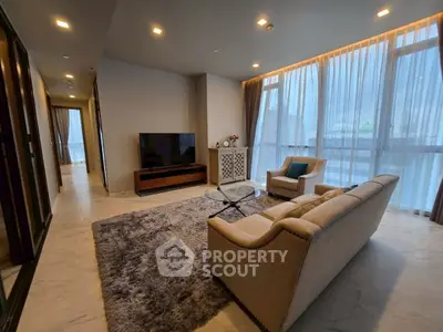 Luxurious modern living room with plush seating and large TV, featuring floor-to-ceiling windows and elegant decor.