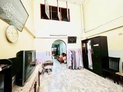 Spacious living area with high ceilings and traditional decor, featuring ample natural light and tiled flooring.