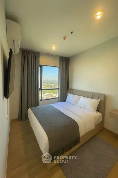 Modern bedroom with large window and stylish decor in a high-rise apartment.