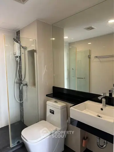 Modern bathroom with sleek fixtures and glass shower enclosure in a contemporary apartment.