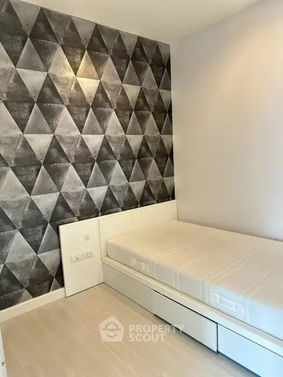 Modern bedroom with geometric accent wall and sleek white furniture