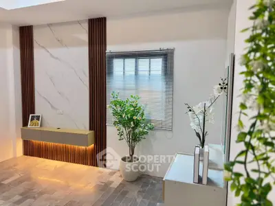 Modern living room with stylish decor, featuring a marble accent wall, sleek blinds, and elegant indoor plants.