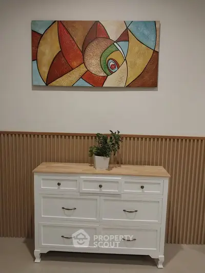 Stylish interior with modern art and elegant white dresser in a cozy living space.