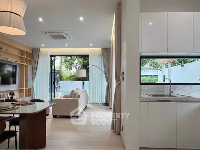 Modern open-plan living room and kitchen with large windows and stylish decor