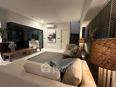 Modern living room with stylish decor and ambient lighting, featuring a cozy seating area and contemporary artwork.
