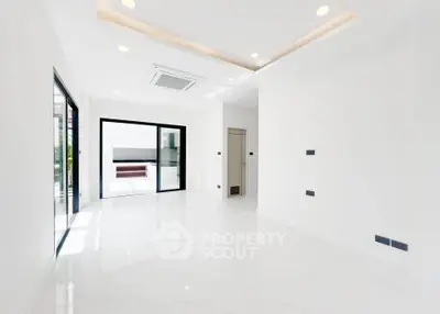 Spacious modern living room with sleek white flooring and large windows for natural light.