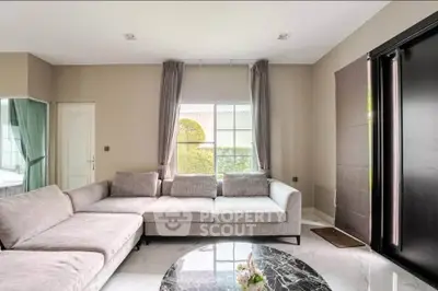 Spacious living room with modern gray sofa and marble coffee table, featuring large window with garden view.