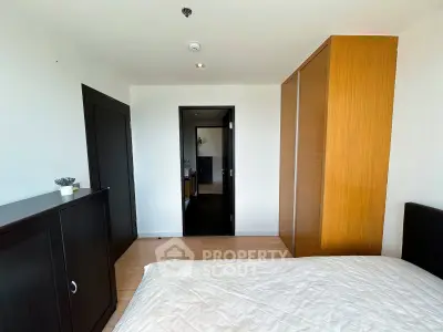 Modern bedroom with wooden wardrobe and sleek black door, showcasing minimalist design and natural light.