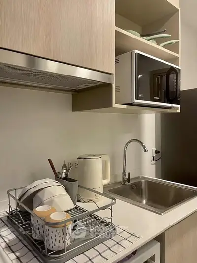 Modern kitchen with sleek cabinetry, microwave, and stainless steel sink, perfect for urban living.