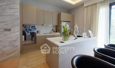 Modern kitchen with sleek cabinetry and island, featuring elegant decor and natural light.