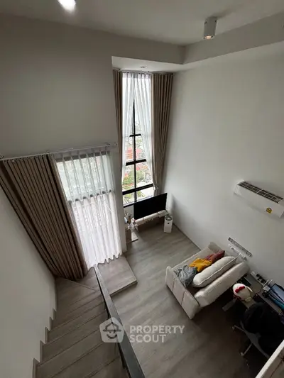 Modern loft-style living room with high ceiling and large window view