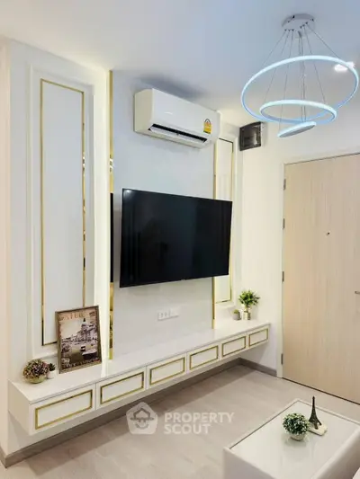 Modern living room with sleek TV setup and stylish lighting in a contemporary apartment.