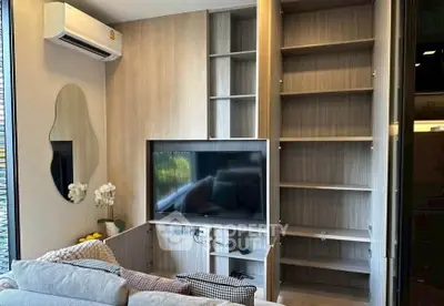 Modern living room with built-in shelves and TV, featuring stylish decor and air conditioning.