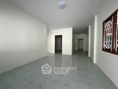 Spacious empty room with tiled floor and white walls, ideal for customization.