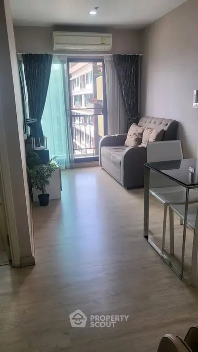 Modern living room with balcony view, featuring sleek furniture and natural light.