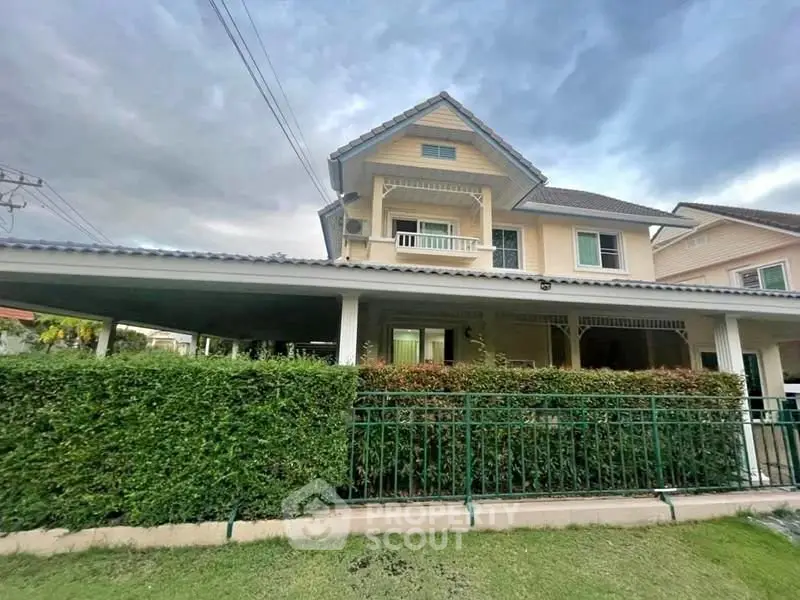 Charming two-story house with lush garden and spacious carport in a serene neighborhood.