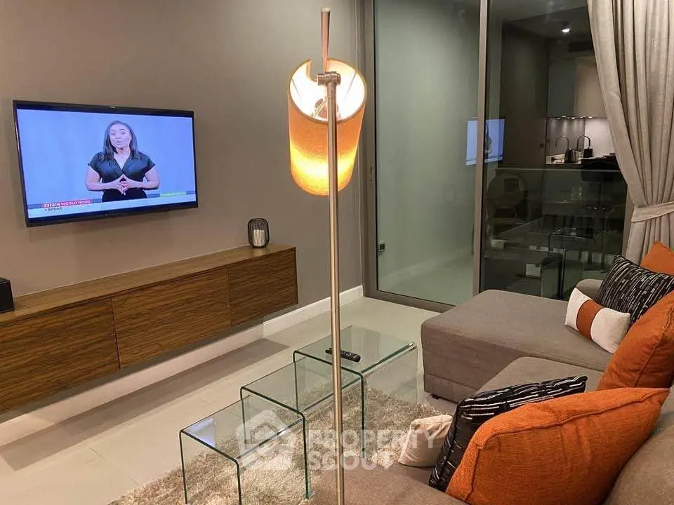 Modern living room with stylish decor and glass coffee tables, featuring a wall-mounted TV and cozy seating.