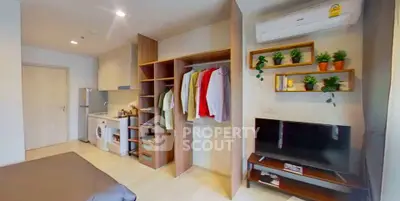 Modern studio apartment with open wardrobe, compact kitchen, and cozy living area.