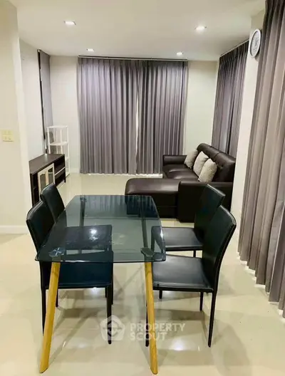 Modern living room with glass dining table and cozy seating area, perfect for stylish urban living.