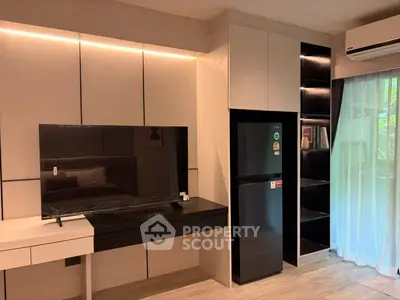 Modern living room with sleek TV, fridge, and air conditioning