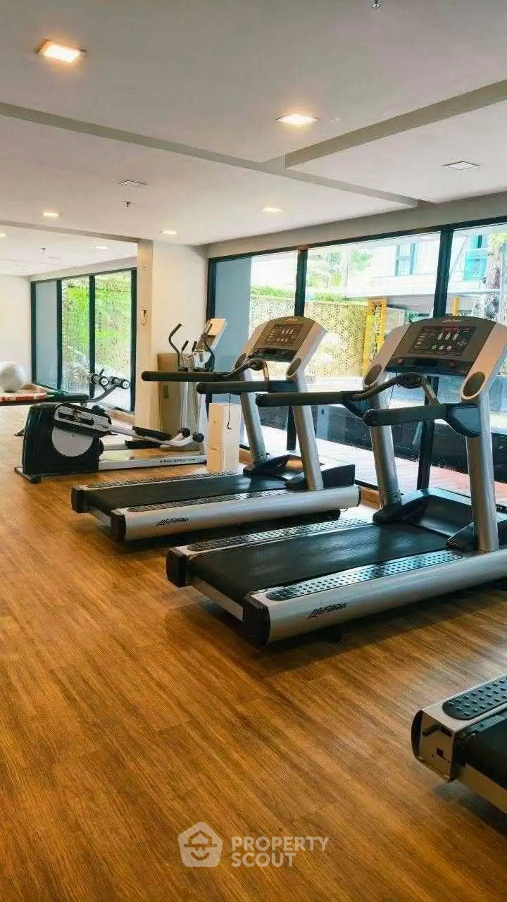 Modern gym with state-of-the-art treadmills and large windows in a luxury apartment complex.