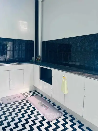 Charming kitchen with stylish black and white tile flooring and sleek cabinetry.