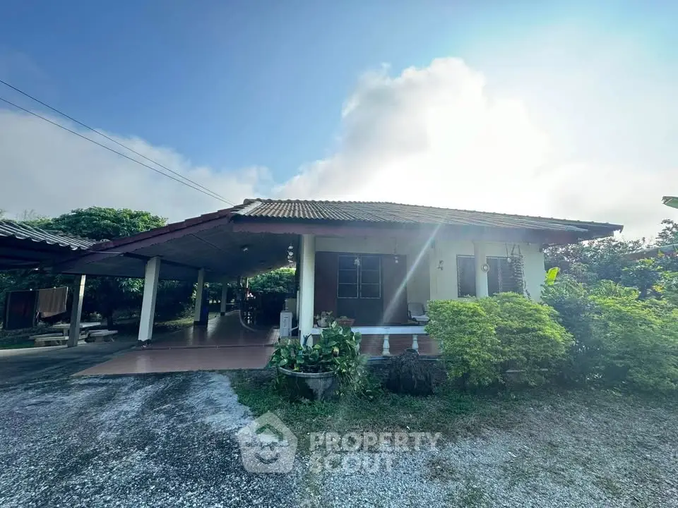 Charming single-story home with spacious carport and lush greenery.