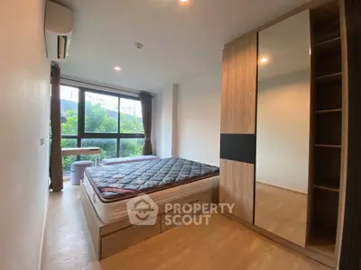 Modern bedroom with large window and stylish wardrobe, offering a serene view of greenery.