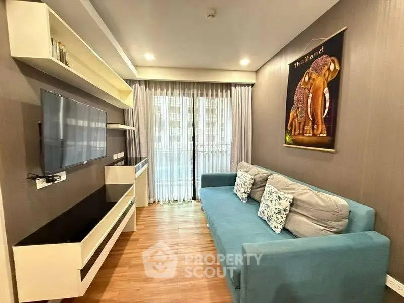 Modern living room with stylish decor and large window, featuring a cozy blue sofa and wall-mounted TV.