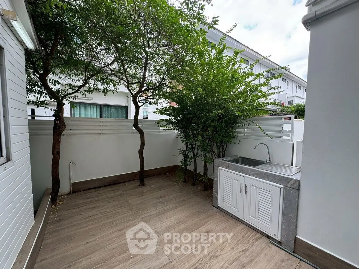 Charming outdoor patio with sink and lush greenery, perfect for relaxation and entertaining.