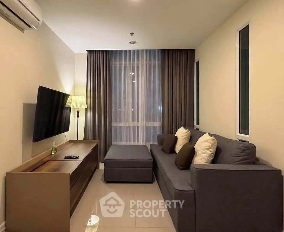 Cozy living room with modern gray sofa, flat-screen TV, and elegant floor lamp, perfect for relaxation.