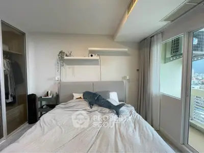 Modern bedroom with balcony access and stylish decor, featuring a cozy bed and ample natural light.