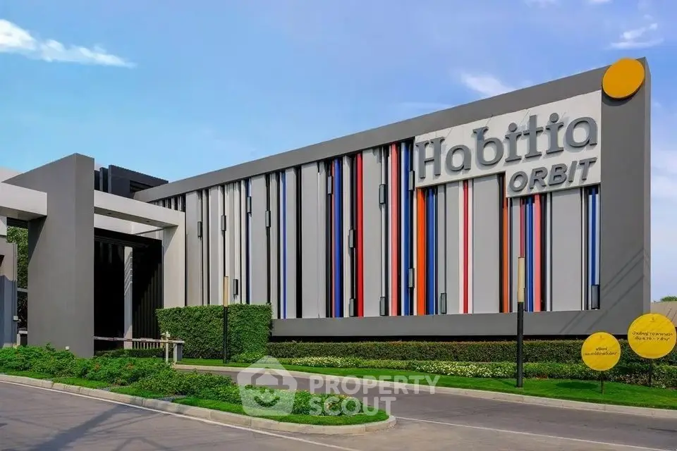 Modern building exterior with colorful facade and lush landscaping.