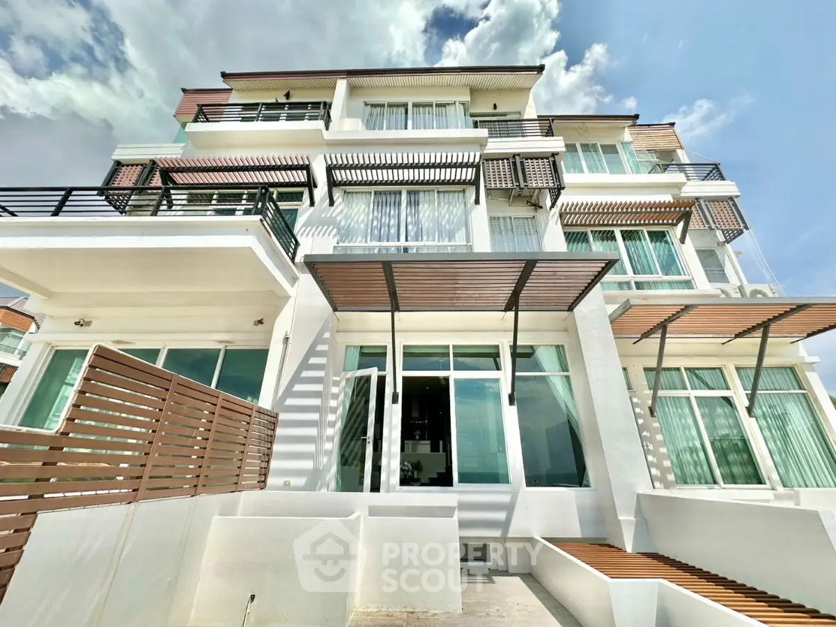 Stunning modern multi-story building with large windows and stylish balconies under a clear blue sky.