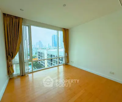 Spacious empty room with large windows offering stunning city views in a modern apartment.