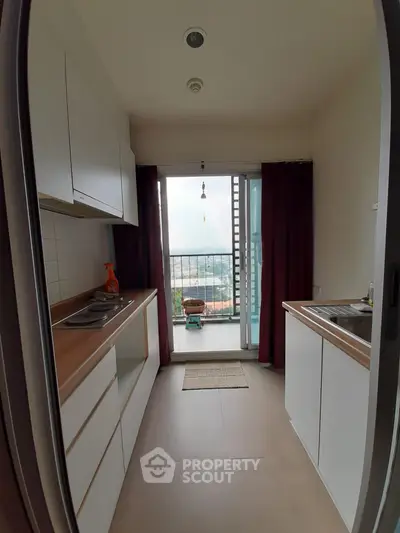 Modern kitchen with open layout and balcony view, featuring sleek cabinetry and natural light.