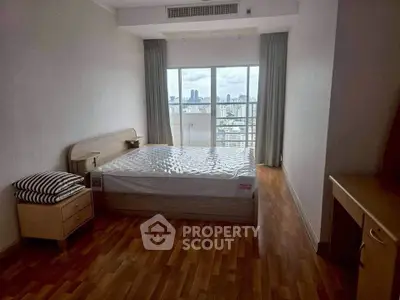 Spacious bedroom with city view and wooden flooring in modern apartment