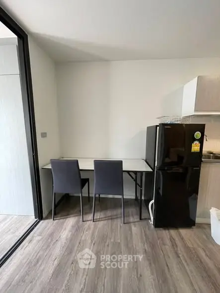Modern kitchen with sleek black fridge and dining area in stylish apartment.