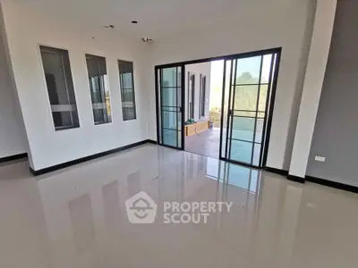 Spacious modern living room with large windows and sliding glass doors leading to a balcony.
