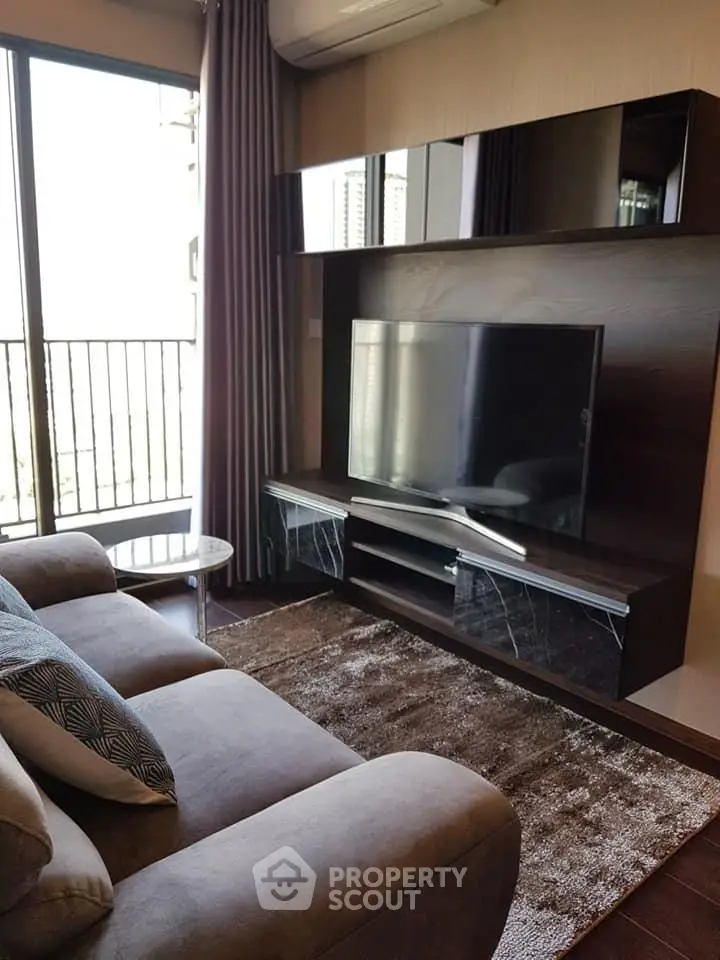 Modern living room with sleek TV unit and cozy sofa, featuring large windows and balcony access.