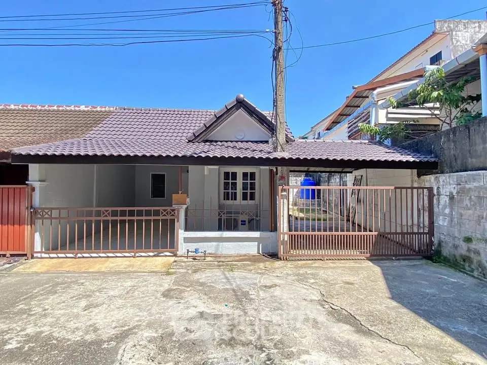 Charming single-story house with gated entrance and tiled roof in a serene neighborhood.