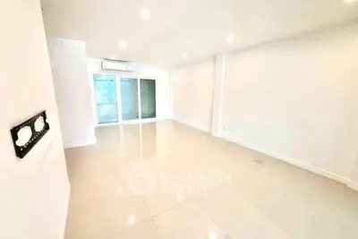Spacious modern living room with bright tiles and large windows in a contemporary apartment.