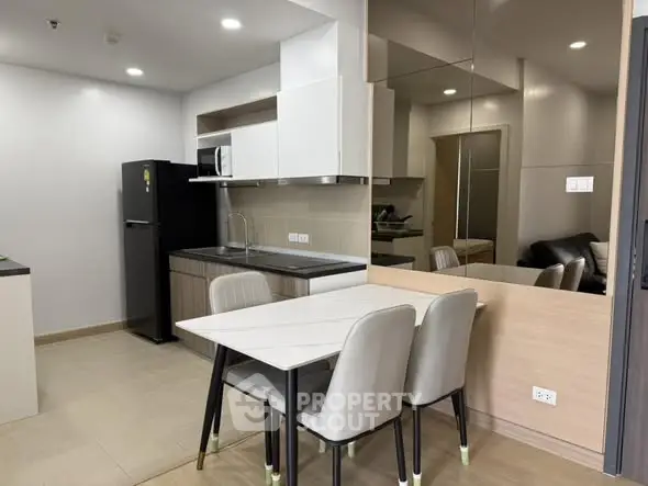 Modern kitchen with sleek design and dining area in contemporary apartment.